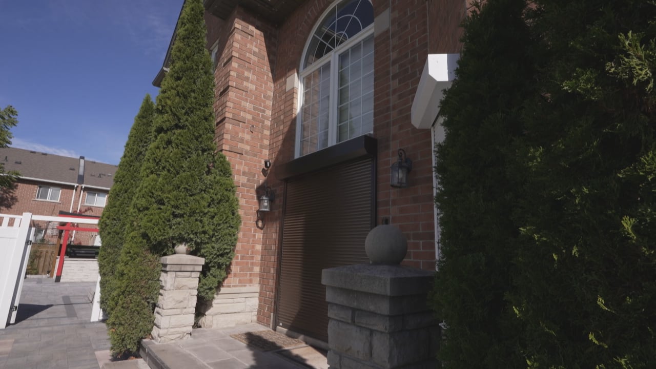 Metal shutters cover the doorway to a standalone home. 