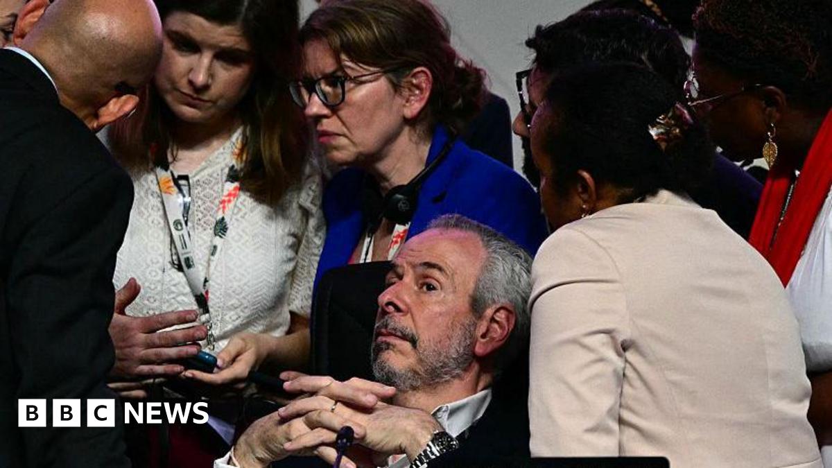 A bearded man, COP president Andre Correa do Lago lies back as several others surround him, looking worried, during  a critical moment in the COP30 talks