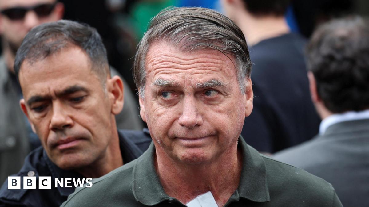 Former Brazilian President Jair Bolsonaro wearing green polo shirt with police officer standing behind him
