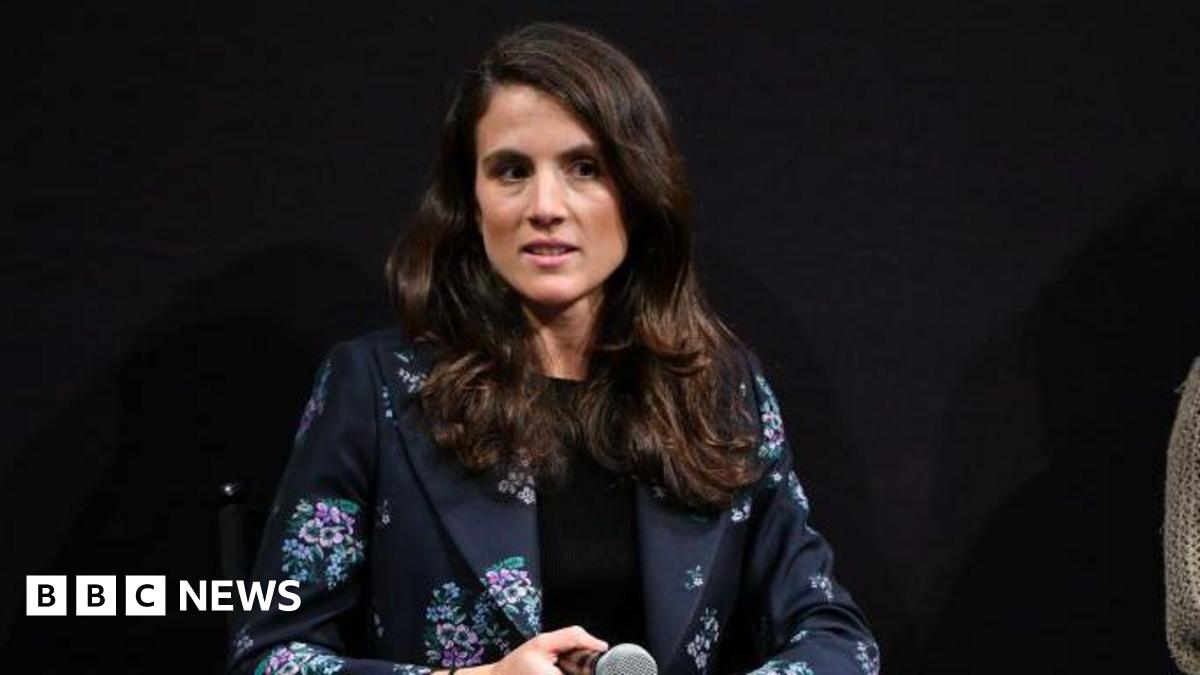Schlossberg holding a microphone at a speaking event