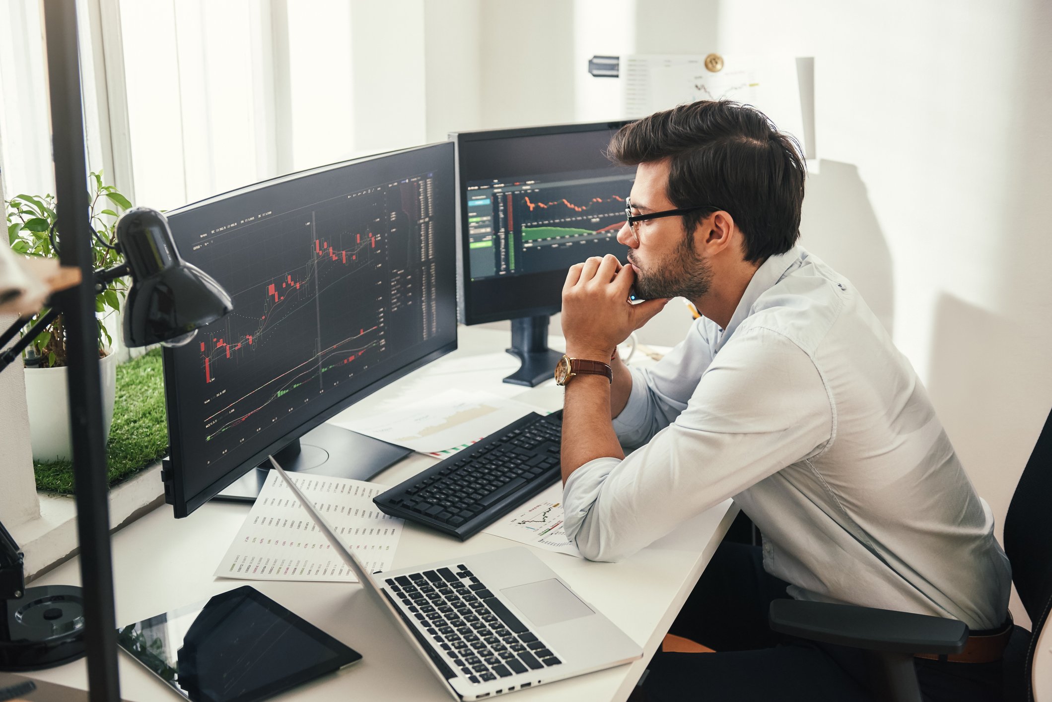 Person sitting at a desk looking at two monitors.