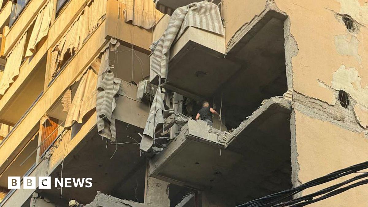 A view from below shows a man walking on the floor of a destroyed balcony after an Israeli military strike targeted a residential apartment block in southern Beirut.