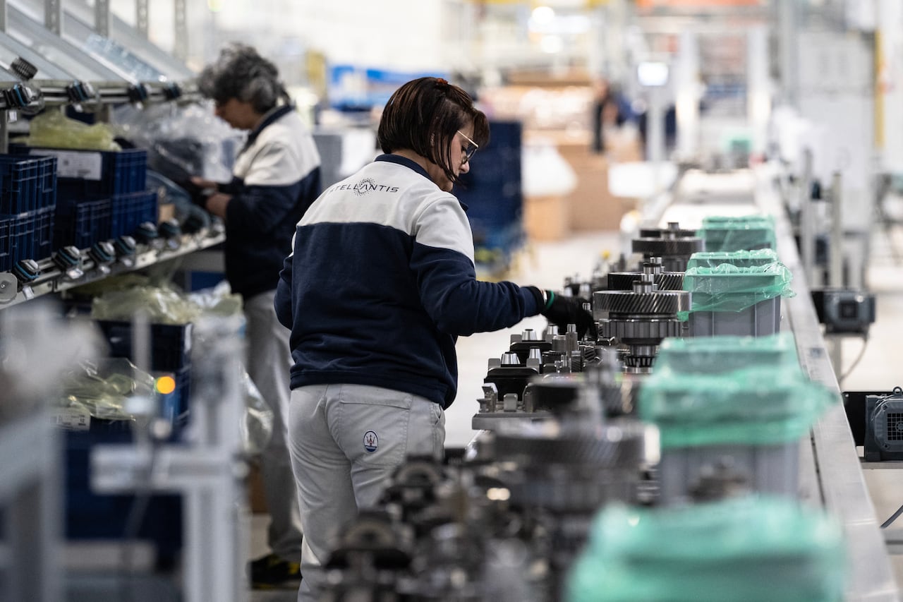 Employee walks along an assembly line of components for plug-in hybrid vehicles. 