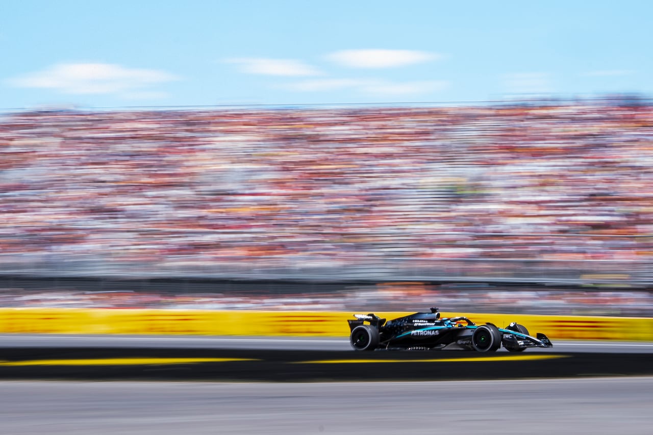 A formula one car races so fast it blurs crowd