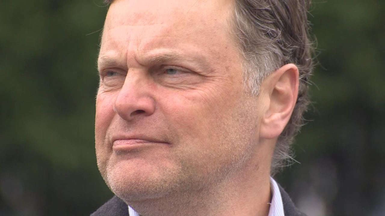 A white man with a light stubble looks to his right.