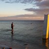 A person fishes next to a broken pier.