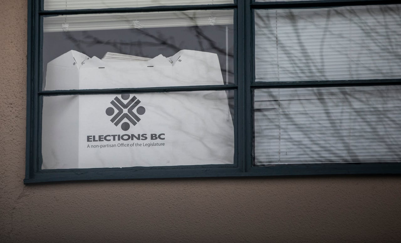 A piece of paper reading 'Elections BC A non-partisan office of the Legislature' is seen on a window.
