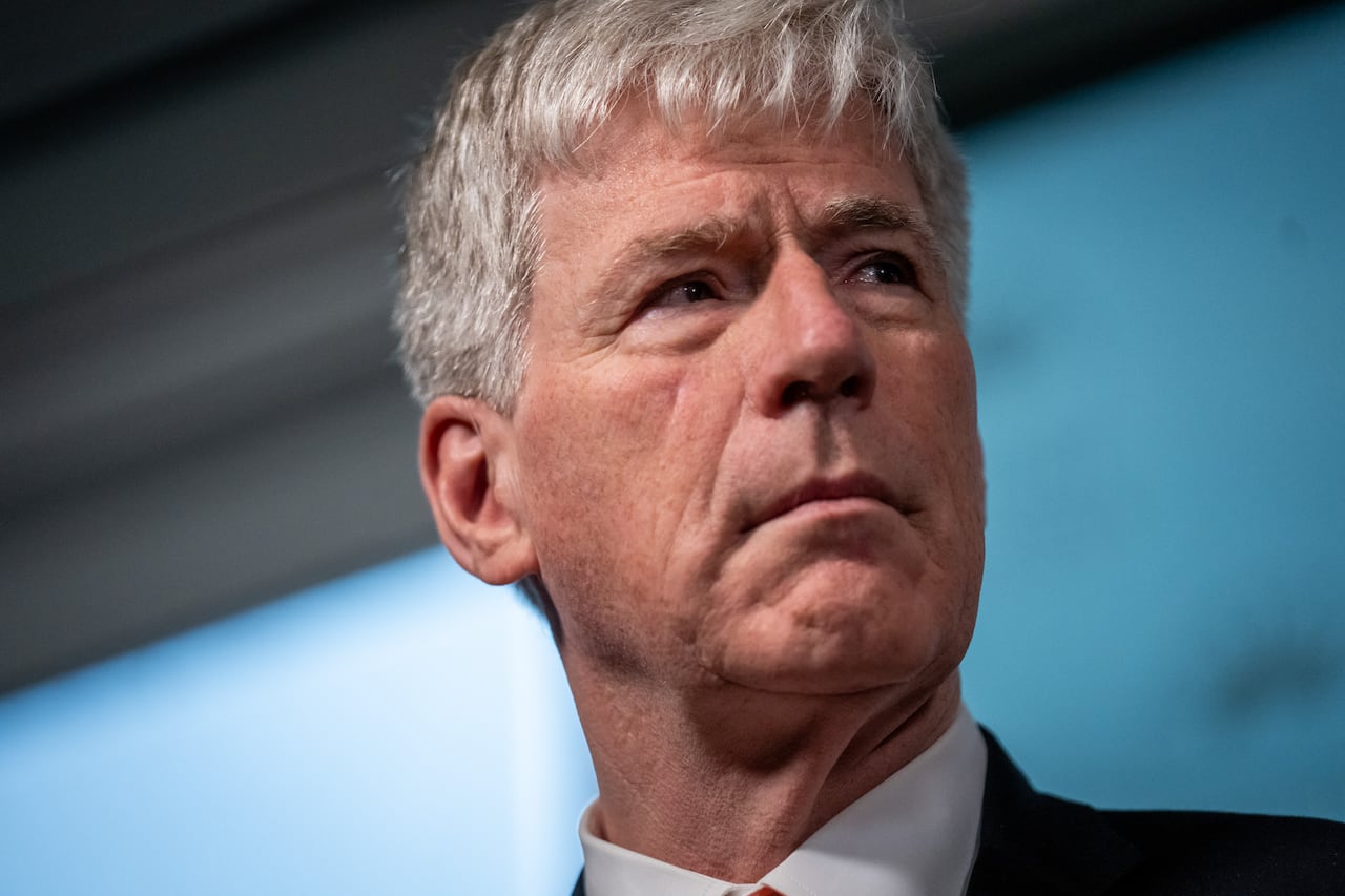 A close-up photograph of a white man with white hair looking to his left.