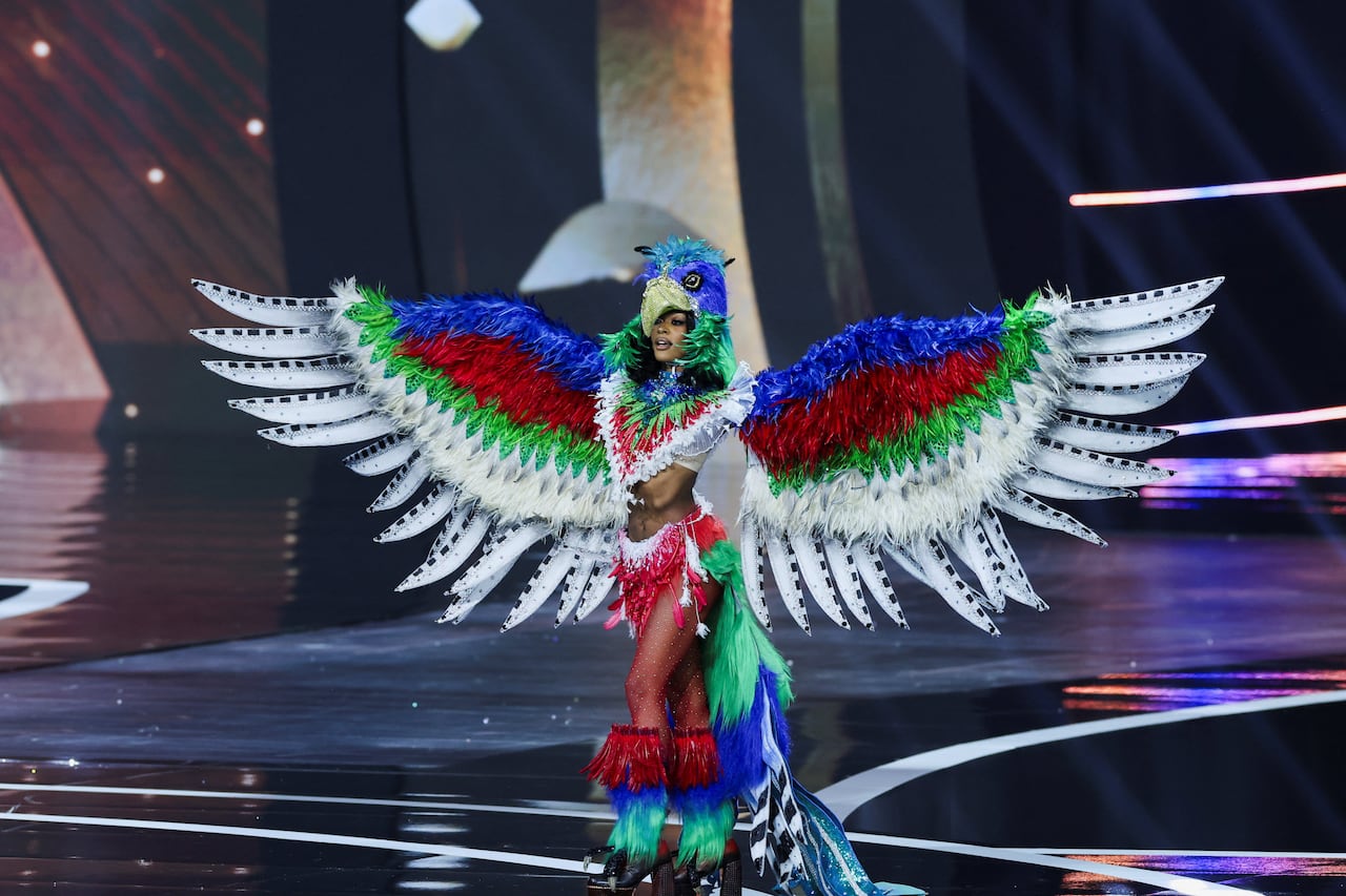 A woman in a feathered costumes walks on  a stage