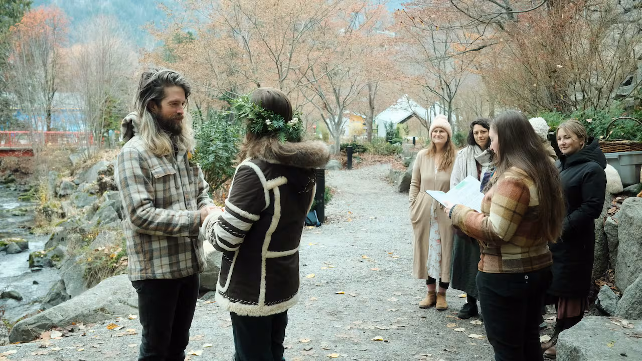 Two people stand holding hands while others look on