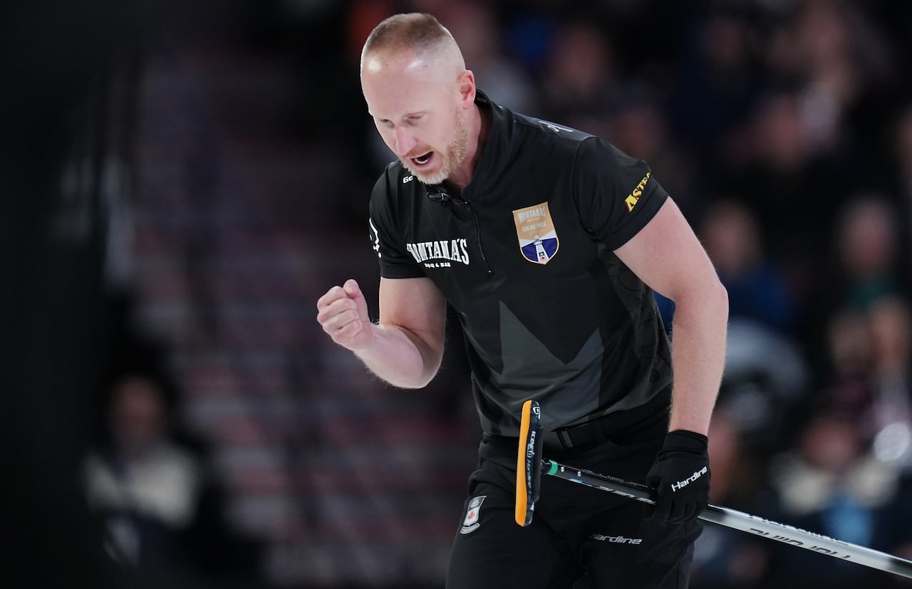 A man in a curling uniform pumps his fist.