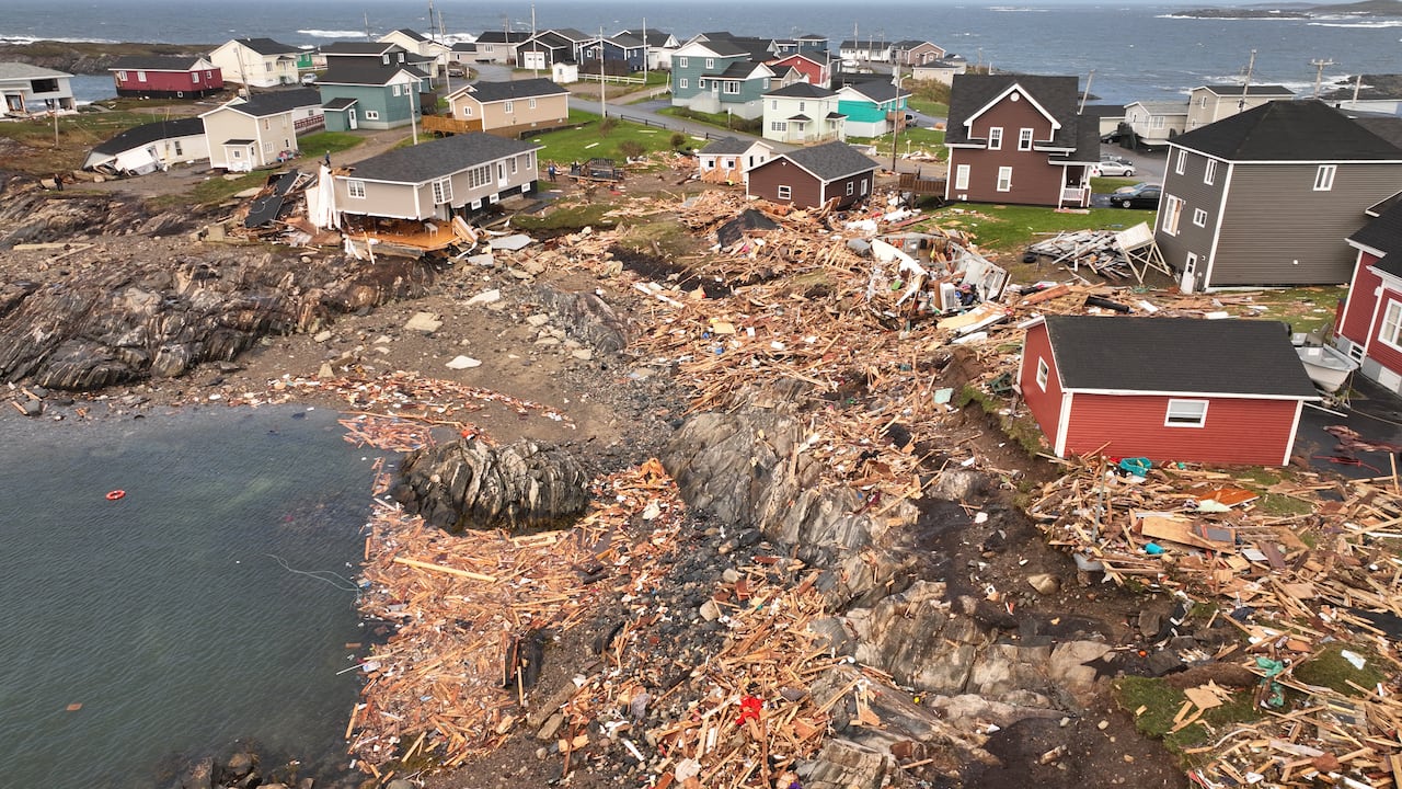 Aerial shot of colourful houses on coastline surrounded by wood and debris
