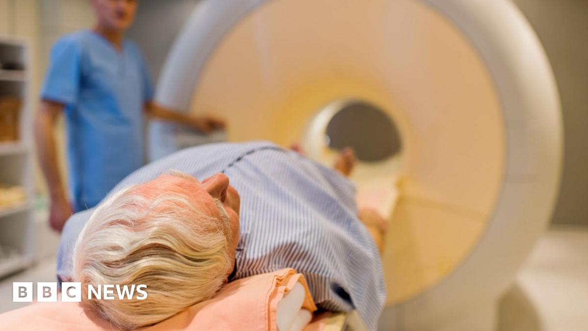Man with grey hair lying down about to enter an MRI machine.