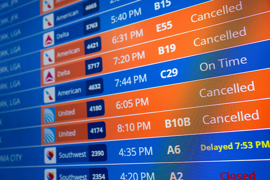 Flight timings and cancellations are displayed on a departures board