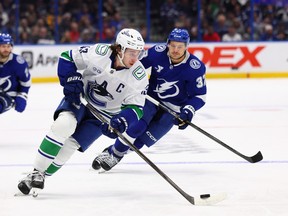 Quinn Hughes is chased by Yanni Gourde during the second period at Benchmark International Arena