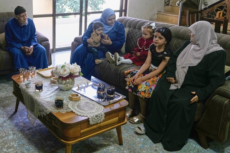 A family sits in a living room. From left are Mohammad’s father Waleed Husein Ali, wife Hadeel, son Bara’, daughter Misk, an unidentified relative, and Mohammad’s mother Sobheya Husein Ali.