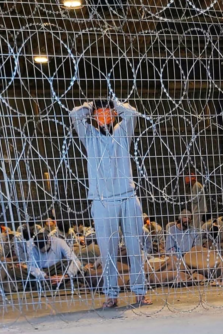 blindfolded prisoners behind barbed wire