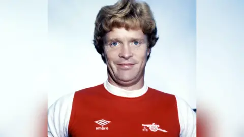 SNS Willie Young in a red and white Arsenal shirt.