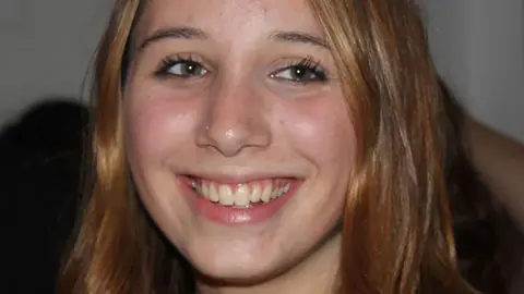 Figueiredo family Alice Figueiredo, a young woman with long blonde hair, smiles and looks slightly off-camera