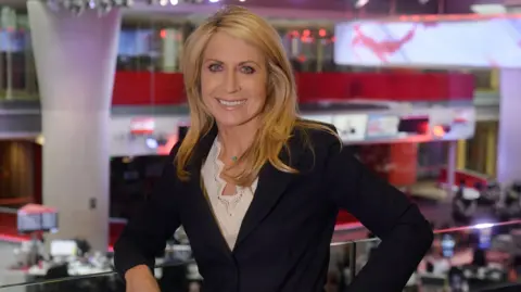 Jeff Overs / BBC Deborah Turness leans on a rail above the BBC newsroom