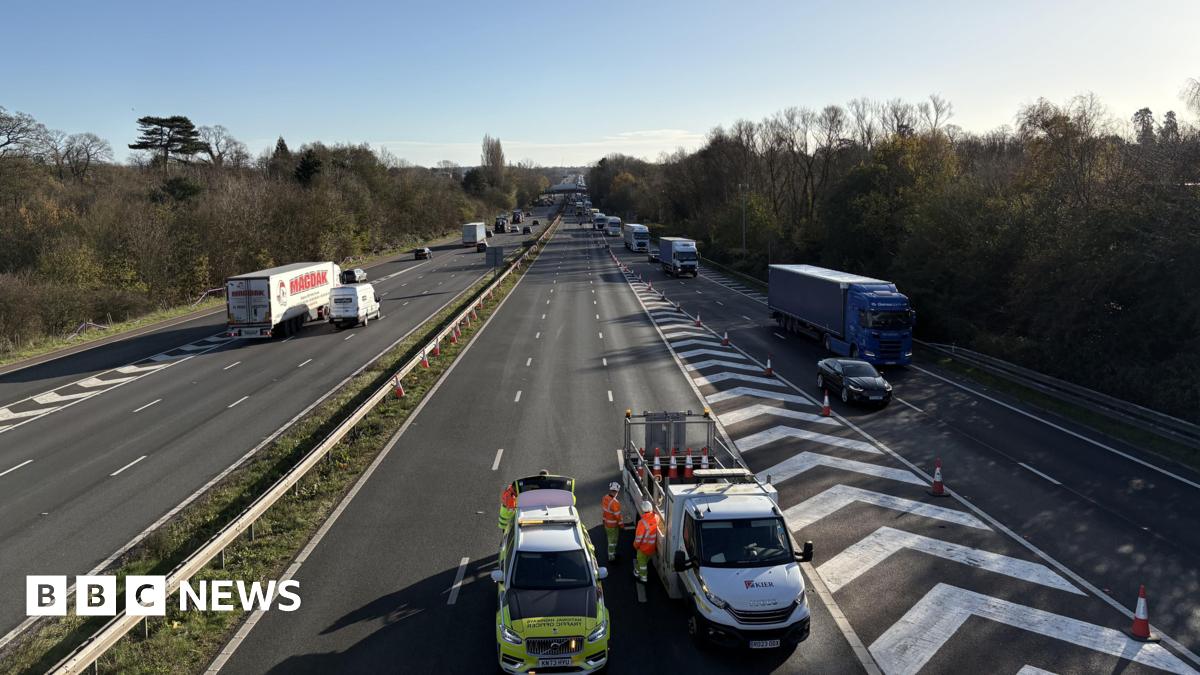 A picture of a motorway from a bridge above. The coastbound carriageway, on the left, is open with traffic flowing. The London-bound carriageway, on the right, is blocked off by Highways Officers and traffic is exiting via a slip road.