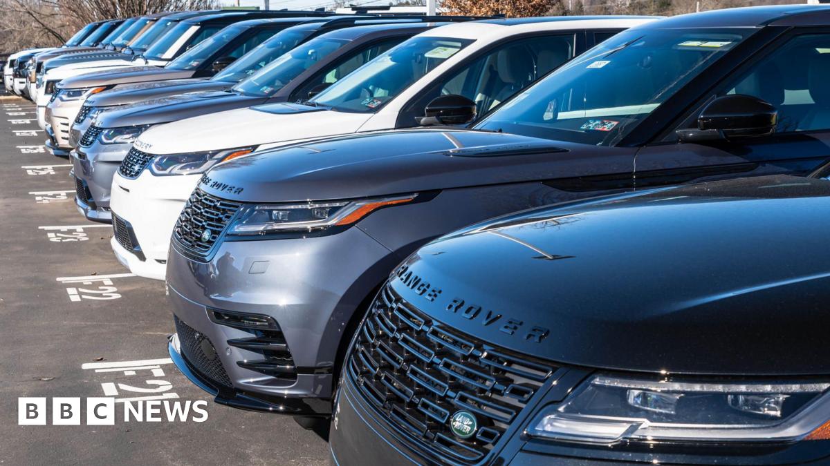 A line of Range Rover cars in a dealership car park