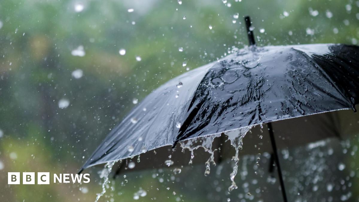A stock image of rain falling on a black umbrella.