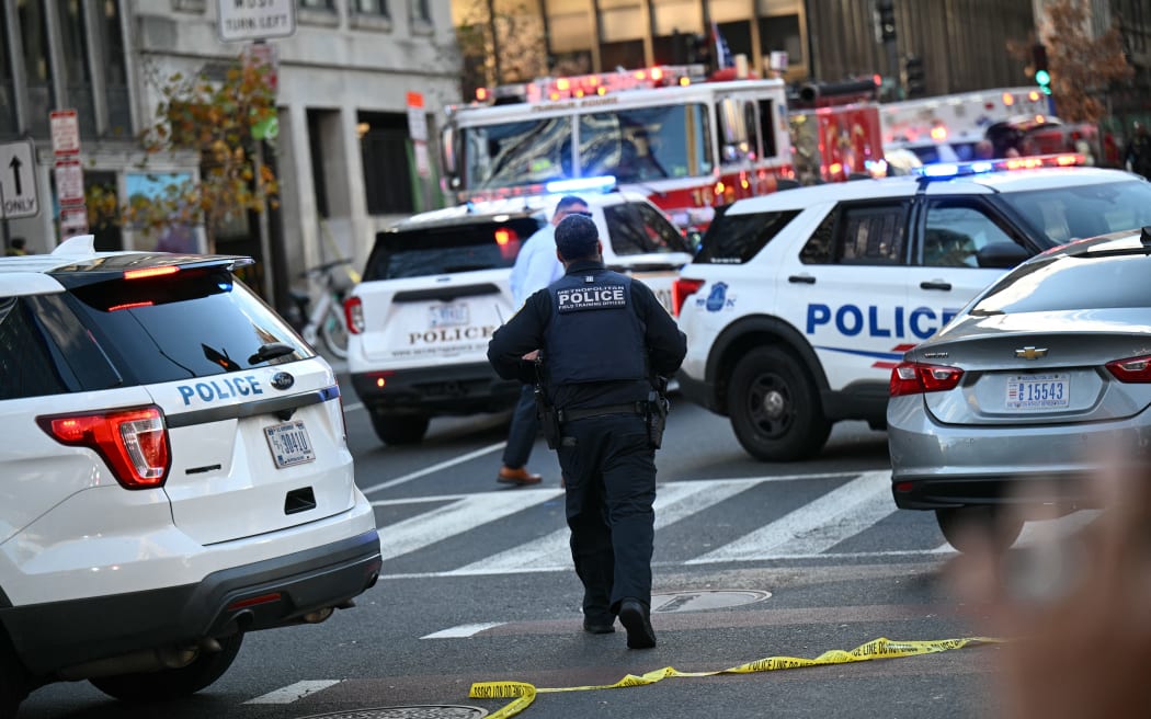 A Metropolitan Police officer walks between patrol cars near a crime scene after a shooting in downtown Washington, DC, on November 26, 2025. Two members of the National Guard were shot Wednesday just blocks from the White House, according to officials, as a spokesperson for Donald Trump said the president has been briefed on the 