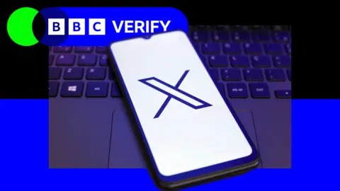 BBC A mobile phone with the 'X' logo next to a laptop keyboard