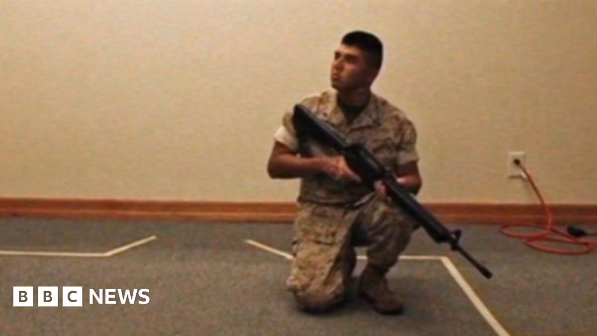 A young woman is seated looking straight at the camera. She is wearing a black robe, a black headscarf and a black veil that covers most of her face, leaving just her eyes visible. A bit of a pale pink scarf can be seen under the veil.