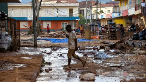 EPA/Shutterstock A person walks down a street affected by Hurricane Melissa; in Santa Cruz, Jamaica, 30 October 2025.