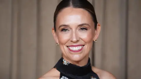 PA Media A woman at a red carpet event. She has dark hair and is wearing a black dress.