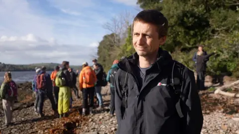 A man looking towards the camera with a large group of people behind him.