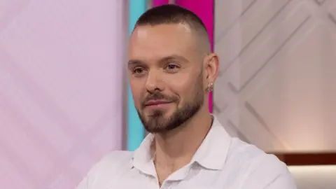 Shutterstock/ITV John Whaite pictured on ITV's Lorraine in August 2023, wearing a white shirt and looking straight ahead
