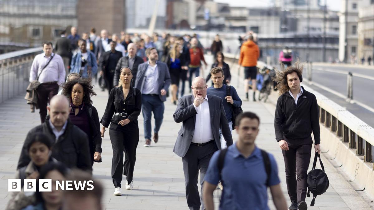 People in suits and casual outfits walk across a bridge on a sunny day.