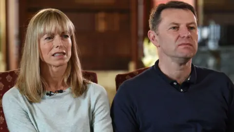 Joe Giddens/PA Wire Kate McCann, in a light grey top, sits to the left of Gerry McCann, who is wearing a dark polo top and jumper