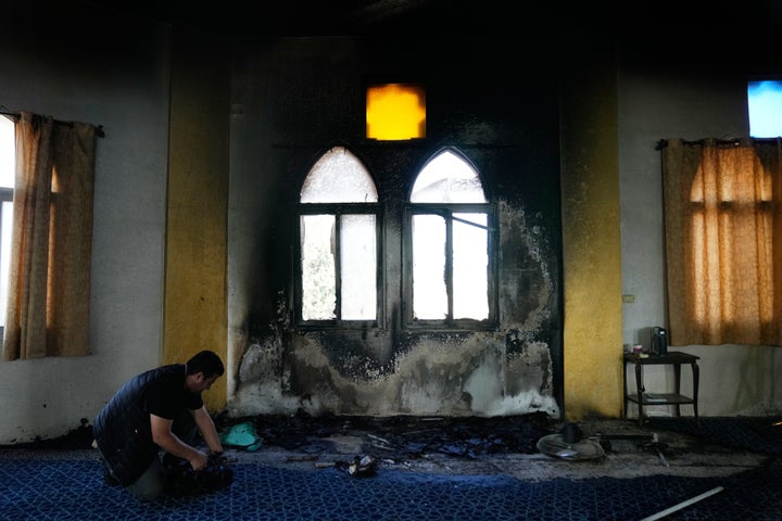 A video journalist works by a burnt indoor section of a mosque that was torched and defaced by Israeli settlers overnight, in the West Bank town of Deir Istiya Thursday, Nov. 13, 2025. (AP Photo/Nasser Nasser)