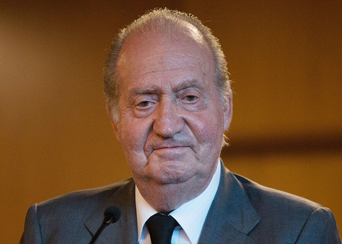 Former King Juan Carlos in a formal suit, speaking at an event about his brother’s life and revealing personal details.