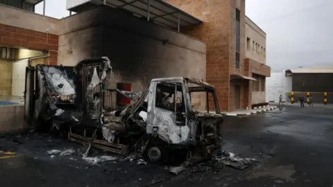 EPA The burned-out wreck of a lorry at an industrial area following an attack by Israeli settlers in al-Ladain, near Beit Lid village, in the occupied West Bank (11 November 2025)