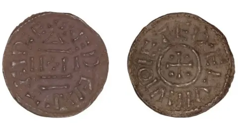 Andrew Williams/Norfolk County Council The front and back of a brown coin side by side. The first has what appear to be ancient runes on, the second as a plus sign in a circle and what looks like ancient runes around it. 