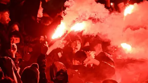 SNS Images Hooded Aberdeen fans setting off pyrotechnics during a match between Dundee United and Aberdeen in Dundee