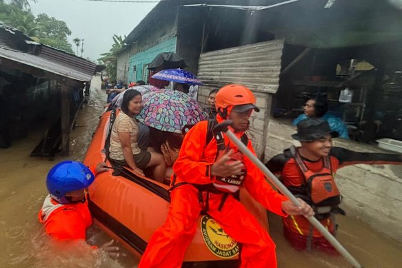 Rescuers from the Indonesian National Search and Rescue Agency evacuate people from their flooded home in North Sumatra province.