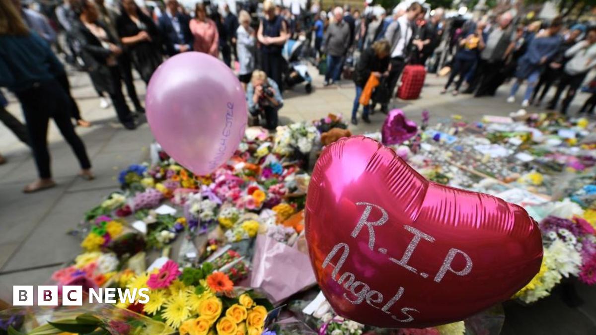 Tributes to the victims of the Manchester arena attacks are shown filling the city centre in 2017, with members of the public looking at a huge number of flowers and pink balloons filling a city centre street.