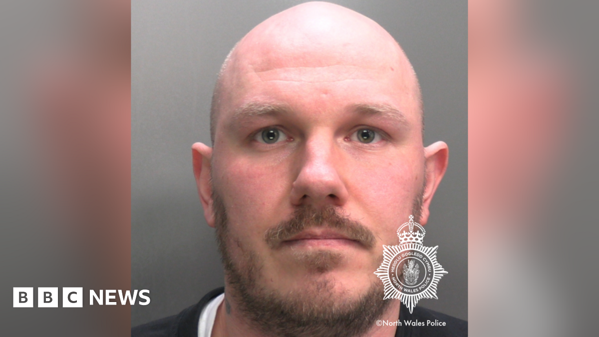 A police mugshot of Miles Cross, a bald man with a beard and moustache.