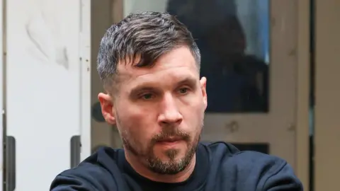 Collins Photos Dublin Garrett Pollock has short dark and grey hair and a beard with grey and brown hairs. He is wearing a black sweatshirt.