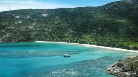 AFP via Getty Images An aerial photo taken on April 4, 2024, shows a boat anchored near coral around Lizard Island on the Great Barrier Reef.