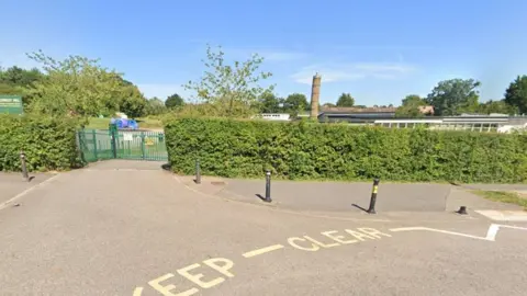 Google The school seen from the road outside - you can mostly just see a hedge and the green school gates.
