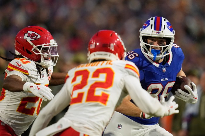 Buffalo Bills tight end Dalton Kincaid (86) runs with the ball as Chiefs defenders close in.