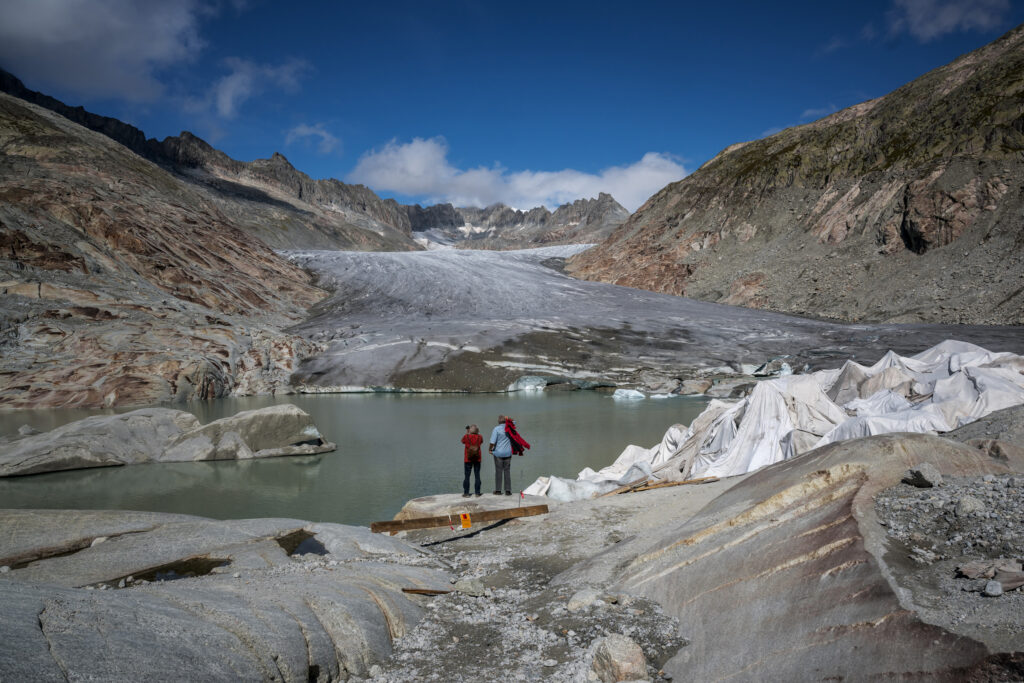 People observe the Rhone Glacier as it melts into its glacial lake in the Swiss Alps. Credit: Fabrice Coffrini/AFP via Getty Images