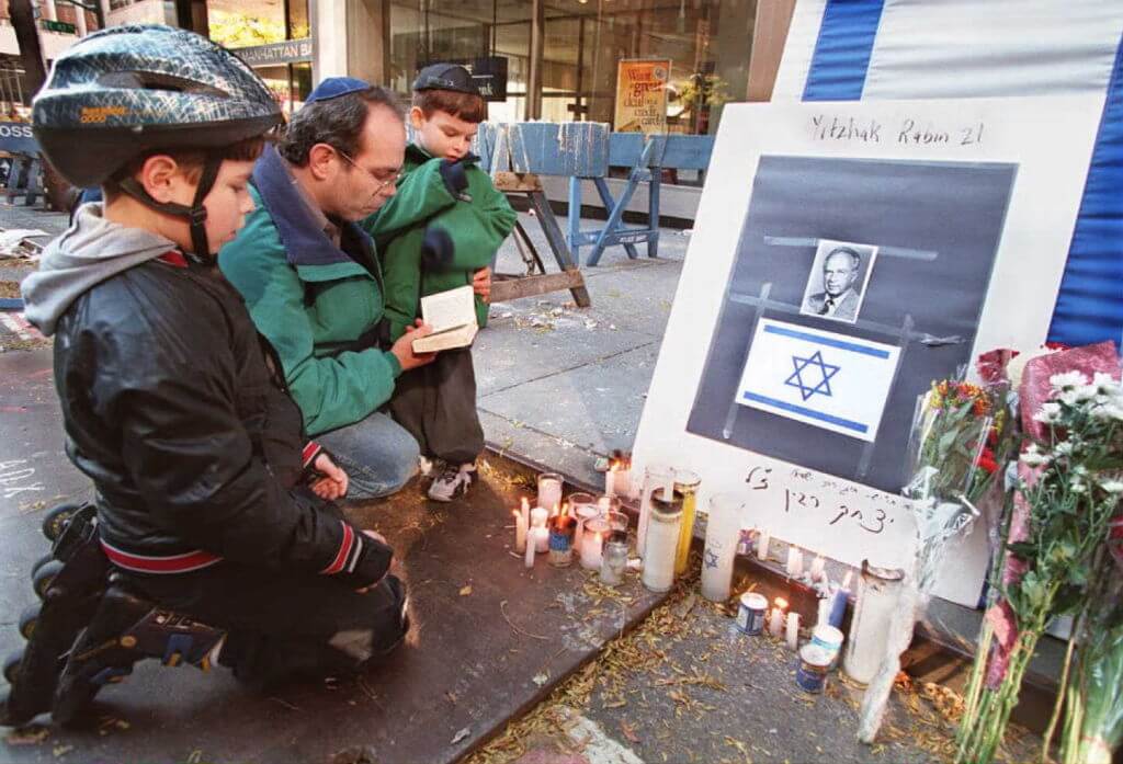 Robert Marx leads his sons Joshua and Benjamin in prayer next to a makeshift memorial to Israeli Prime Minister Yitzhak Rabin, in front of the Israeli consulate in New York on Nov. 5, 1995. 